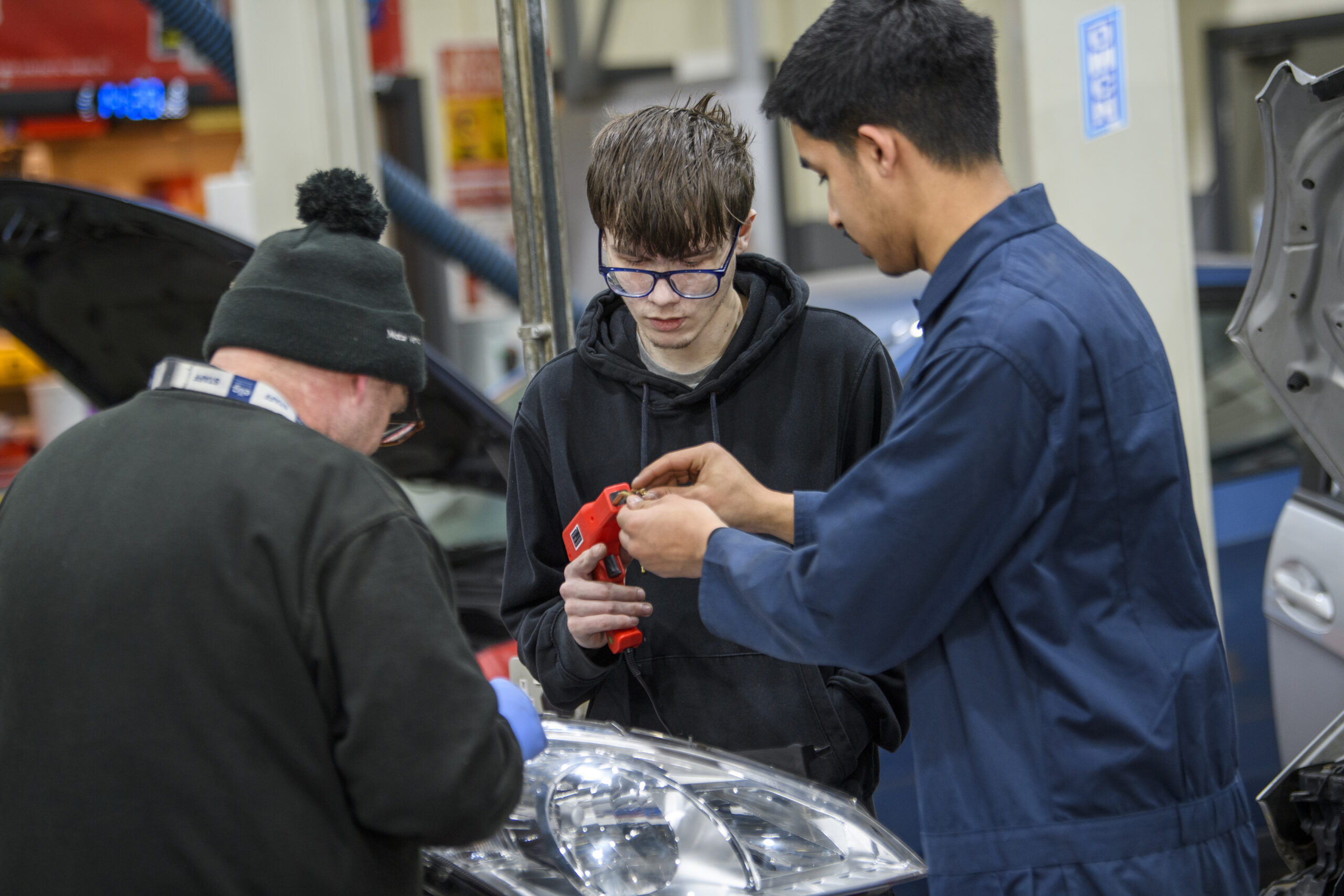 Students working with a tutor and a piece of machinery